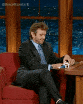 a man in a suit and tie is sitting in a chair playing cards