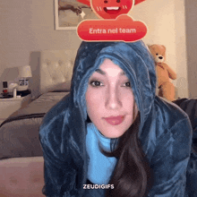 a woman wearing a hooded jacket with a red button that says entra nel team on top of her head