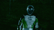 a man in a green and white suit with a helmet on stands in front of a green light