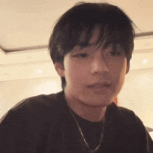 a close up of a young man wearing a black shirt and a chain .