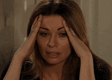 a woman is holding her head with her hands and has a ring on her finger