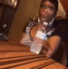 a woman is holding a bottle of water on a table .