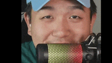 a man wearing a blue hat is holding a microphone in his mouth