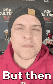 a man wearing a red hoodie and a black beanie has his eyes closed and the caption but then