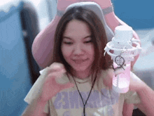 a woman is sitting in a pink chair making a heart with her hands .