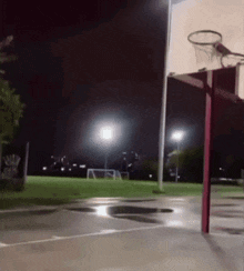 a basketball court is lit up at night with a basketball hoop in the foreground