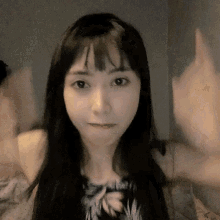 a woman with long black hair is waving her hands
