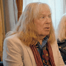 a man with long blonde hair and a scarf around his neck
