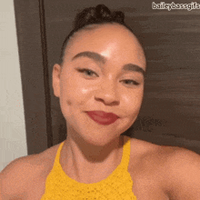 a woman wearing a yellow top and red lipstick is smiling .