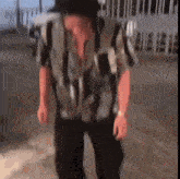 a man wearing a hat and a striped shirt is dancing on a street .