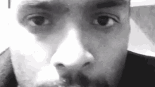 a black and white photo of a man 's face with a beard looking at the camera .