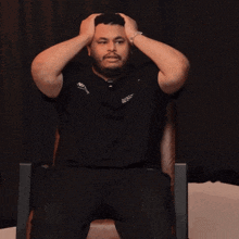 a man is sitting in a chair with his hand on his head wearing a shirt that says nipport