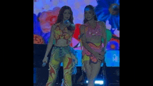 two women are singing into microphones on a stage .