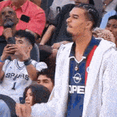 a man in a spurs jersey stands in the stands