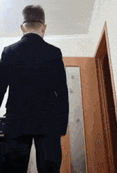 a man in a suit and glasses stands in front of a door