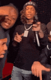 a man is holding a gun in front of a microphone while standing next to two other men .