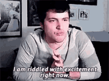 a man is sitting at a table with his hands folded and says `` i am ridded with excitement right now . ''