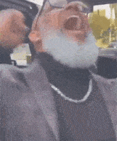 a man with a beard and glasses is sitting in a car .