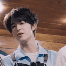 a close up of a young man wearing a blue shirt and overalls