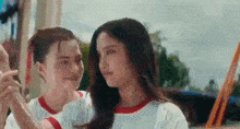 two young women are standing next to each other in a park holding hands .