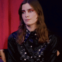 a woman wearing red eye shadow and a black shirt smiles