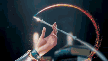 a person 's hand is holding a magic wand with a rainbow coming out of it