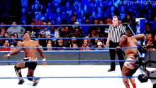 two men are wrestling in a ring with a referee in the background