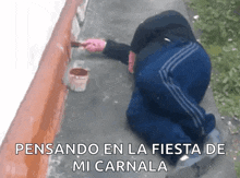 a man is kneeling down and painting a wall with the words " pensando en la fiesta de mi carnal " written below him