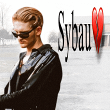 a man wearing sunglasses and a black jacket stands in front of a broken heart and the word sybau