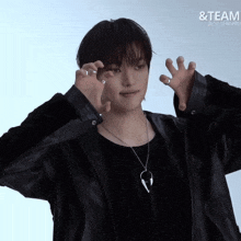 a man wearing a black jacket and a necklace with the word team on the bottom right