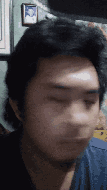 a close up of a man 's face with a picture of a man on the wall behind him