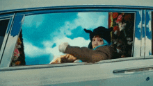 a person is sitting in a car looking out of the window .