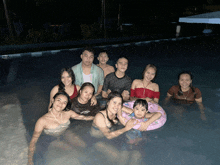 a group of people in a swimming pool with one wearing a shirt that says ' guess '