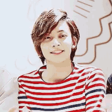 a young man wearing a striped shirt with his eyes closed .
