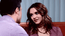 a man and a woman are looking at each other and the woman is wearing a purple shirt