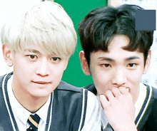 two young men are standing next to each other with one covering his mouth