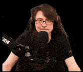 a woman wearing glasses and headphones is sitting in front of a microphone and says eat my whole ass .