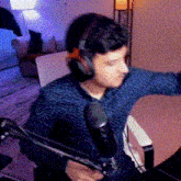 a man is wearing headphones and holding a microphone while sitting in front of a computer .