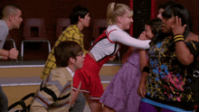 a group of people are standing around a girl in a cheerleading uniform