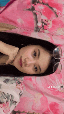 a girl wearing glasses is laying on a bed