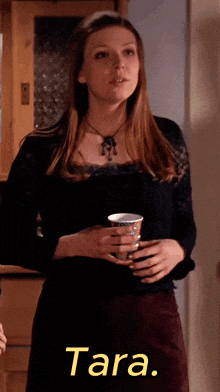 a woman holding a cup with tara written on the bottom right