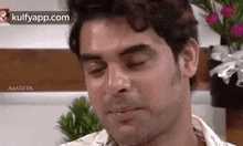 a man is making a funny face with his eyes closed in front of flowers .