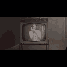 a black and white photo of a woman talking on a telephone on a television screen .