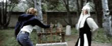 a woman in a blue jacket is fighting a man in a white robe