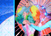 a drag queen in a colorful feathered outfit is dancing on a stage ..