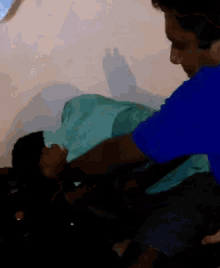 a man in a blue shirt is holding a woman in a green blanket
