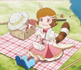 a little girl is sitting on a picnic blanket with a box of food