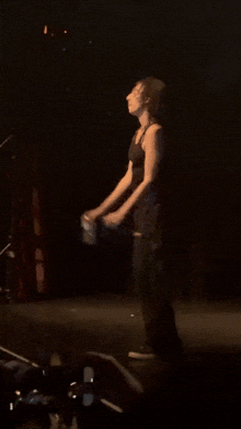a man in a black tank top stands on a stage in front of a crowd