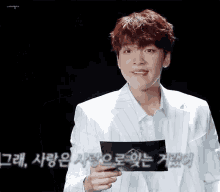a man in a white suit is holding a piece of paper in his hand
