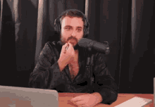 a man wearing headphones is applying lipstick while sitting in front of a microphone